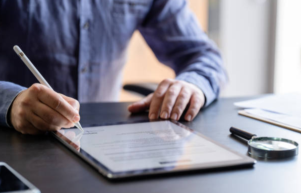 An image of a man signing a document on an iPad.